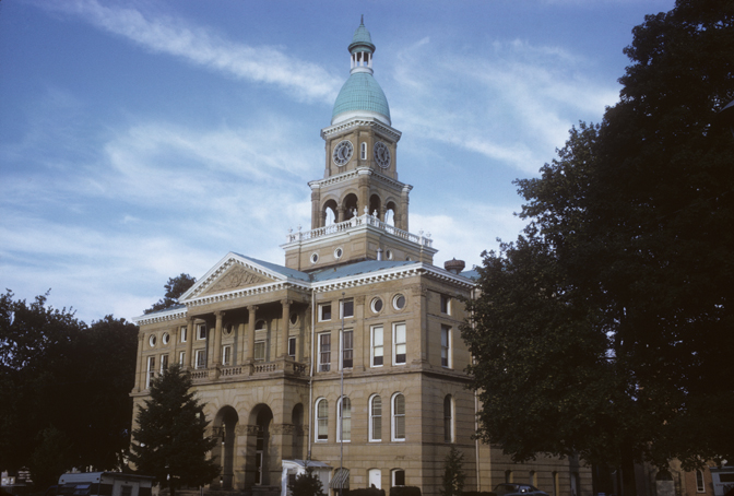 Courthouse border by trees with wispy clouds